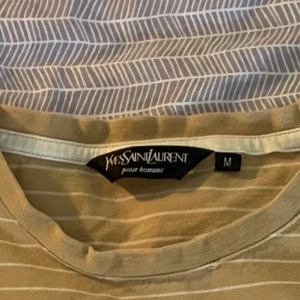 Saint Laurent Tshirt  - Gul/Beige randig Yves Saint Laurent Tshirt med liten logga på bröstet i bra skick Stl M 