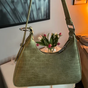 Baguettebag grön  - Baguettebag i superfin grön färg och nice modell som aldrig använts invändigt. Justerbar så man kan fixa längden på axelremmen vilket syns på bild. 2 innerfack säljer pga har för många liknande väskor