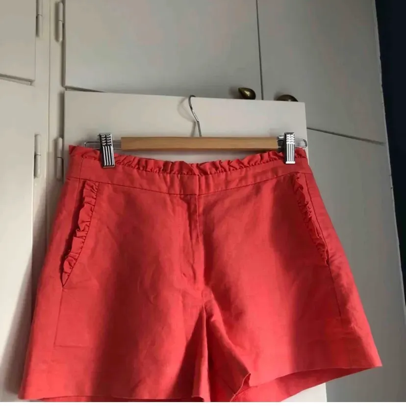 Korallrosa shorts med volanger i linne & bomull från j.crew. Färgen är mer rosa än orange. Väldigt fina till sommaren. Strl 0, passar XS-S. Fraktkostnad tillkommer. Budgivning från 50kr.. Shorts.