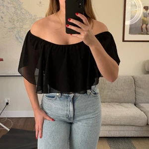 Svart topp/blus  - Jättefin topp/blus som man kan anpassa lite själv med resår runt axlarna så man kan ändra om man vill ha u-urringning eller att den går över axlarna som på bilden. Finns ett tyg under volangerna som man kan vika upp beroende på hur mycket man vill visa av magen. Stretchigt och skönt tyg, storlek motsvarade XS-M 🥰. Har en till i rött!
