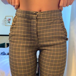 Rutiga kostymbyxor - Rutiga kostymbyxor med söt volang på fickorna. Varsamt använda. 