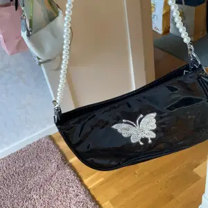 Säljer denna svarta väska med en fjäril där fram. Har aldrig använts. 