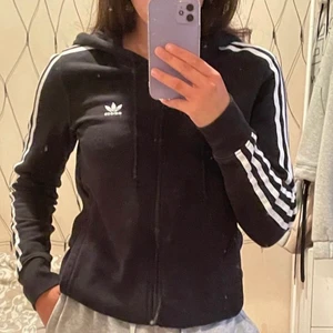 Adidas huvtröja - Säljer denna kofta/munkjacka/huvtröja - vad man nu vill kalla det, från adidas. Den är ny och använd mellan 4-6 gånger. Den är i väldigt gott skick, och har inga som helst fel.  Mycket bra och lång i ärmarna, skulle även passa väldigt bra på en lång person. Mysig å stor huva. Snören som går att dra åt, samt fickor!  Tycker om den väldigt mycket, samt köpte den väldigt dyrt på Boozt, där av det höga priset. Men frakten är inräknad så 270kr är allt du behöver betala. Betalning via swish!
