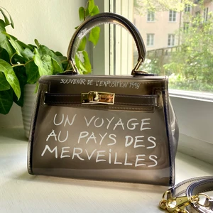 Hermés inspirerad väska  - Populär transparent väska med text på. Axelrem medföljer så väskan kan bäras crossbody. Endast använd 1-2ggr. Skickas spårbart och köparen står för frakten.