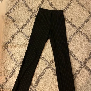 Kostymbyxor från weekday strl 34 - Randiga kostymbyxor från weekday, strl 34. De är långa,  har en slits längst ner med en dragkedja och två fickor framtill med dragkedja. Använda ett fåtal gånger.