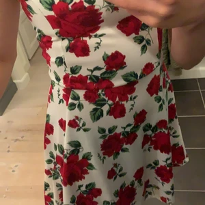 Blommig klänning  - En vit klänning med röda blommar på. Från H&M och är i storlek 34 jämförbart med storlek xs, men kan även passa som en s. Går att pruta