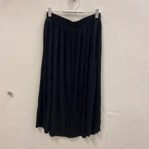 Plisserad kjol - Plisserad svart midi-kjol. Supermjukt material och stretchig i midjan. Aldrig använd. Fler bilder kan tas vid önskemål. Frakt tillkommer