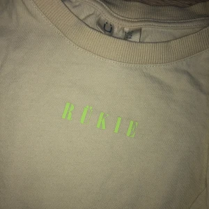 T-shirt - Beige t-shirt med neon grönt tryck från Kappahl! Använd fåtal gånger! Strl 146-152 men funkar fint som XS