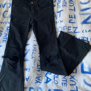 Bootcut byxor - Svarta bootcut byxor i jeansmaterial med hål på knäna och slitningar längst ner. Fickor finns både fram och bak! Använt skick men fortfarande bra kvalité, frakt tillkommer✨💕
