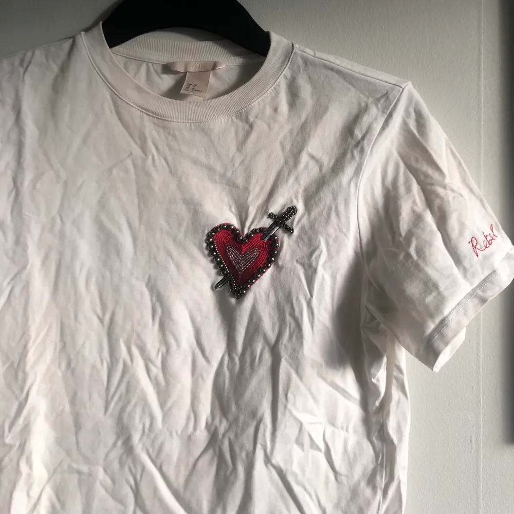 Säljer en vit t-shirt från HM med ett hjärta av pärlor, paljetter och broderi. Skick: använd men hel! Material: 100% bomull. 🌟. T-shirts.