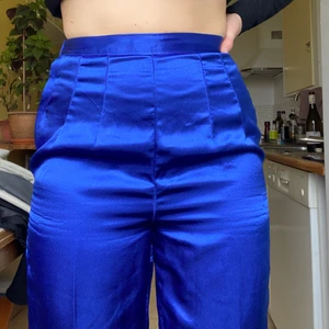 Utsvängda silkesbyxor med detalj  - Jättefina mörkblå silkesbyxor i bootcut-modell! Slits och silverdetaljer på benen! Passar mig som är S / har 27/31-2 i jeans! Dragkedjan har ersatts av tre knappar 
