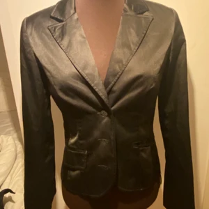 Vintage kavaj - En kavaj som man kan andvänd som en topp då den sitter tight. Den är svart med lite glansigt tyg.