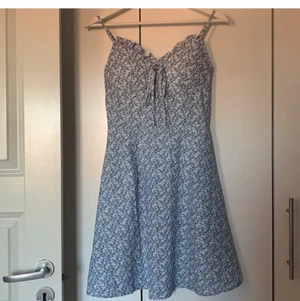 Blommig klänning - Oanvänd vit sommarklänning med blå blommor på som jag köpte in på Plick nyligen, men som tyvärr inte passade mig så bra, jag har A-kupa och den var för stor i bysten. Så synd för jag tycker den är jättefin! Säljaren jag köpte den från hade aldrig använt den och jag har endast testat. Bilderna är tagna av den förra säljaren men kontakta mig om ni vill ha fler bilder/har frågor💓 