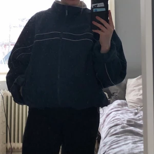 Retro adidas jacka - Mörk blå retro adidas jacka, vet inte var den är köpt. Har band i midjan så den går att dra upp annars är den ganska lång och oversized inga skador, adidas märke fram bak och på ena armen, fickor. Står stl XL men passar mindre då den är snygg oversized.