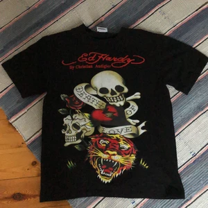 Ed hardy t-shirt - Ed hardy tisha 10/10 cond. Den är storlek L med sitter mer som en M skulle jag säga. Är 181cm o relativt smal och på sista bilden ser ni hur den sitter. 44cm från armhålan och ner