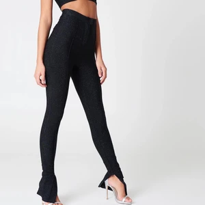 Glittrig festbyxa  - Ett par glittriga tunnare byxor med sömar längst benen och fake fickor på rumpan. NAKD x Vanessa Moe