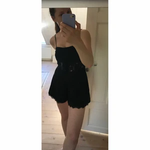 Jumpsuit playsuit svart sommar kjol det svart spets Topshop strl 34 - Jättesöt Jumpsuit / playsuit i svart med knäppning och spetskantade shorts nedtill samt spetsrand i midjan. Perfekt till sommaren, från Topshop (det står strl 36 i men den är ganska liten i storleken och är mer som en strl 34).