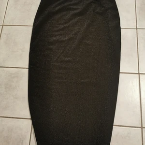 Kjol - Svart kjol med glitter i. Går nedanför knäna ungefär. Storlek s. Formar sig fint av kroppen 