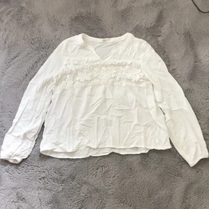 Vit blus - Säljer en vit långärmad blus med blomdetaljer på bröstet. Jag köpte denna blus i Australien och har nästan aldrig användt för att dne blev för liten ganska fort. Den är ganska skrynklig på bilden men om nån vill köpa den så stryker jag den såklart.