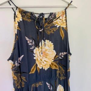 Långklänning i nyskick/ svalt tyg/ storlek L/ bomullsklänning  - Långklänning från Vero Moda helt i nyskick. Storlek L, så 40-42. Normal i storleken och längden. Stängs med ett knytband i ryggen, där man kan reglera längden på banden. Resor nedanför bysten, svalt tyg. Klänningen är blå, med gul-vita blommor. 