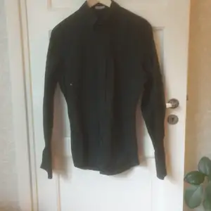svart skjorta Storlek: S. 100% bomull detaljer: små knappar på fram och baksidan