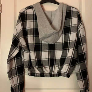 St s - En rutig kofta med luva sitter resor i midjan så den sitter bra. Den är lite kort så går ner till naveln.