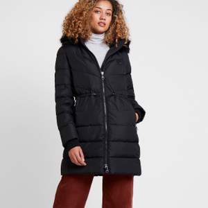 Figursydd vinterkappa från Tommy Hilfiger, modell Alana Padded Coat. Storlek L. Varmfodrad, 100 % polyester. Avtagbar pälskrage, fodrad kapuschong med dragsko och fickor med dragkedja. Nypris: 2 900 kronor. Kvitto finns. Jackan är aldrig använd, helt ny! 