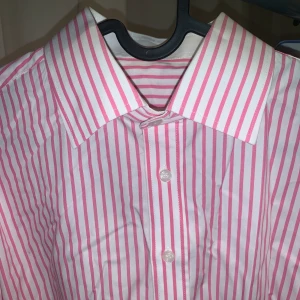 Skräddarsydd randig skjorta  - Skräddarsydd rosa randig skjorta, i bra skick. Sitter som en stl L slim fit (man men passar kvinnor med). Sitter som en oversized skjorta om du har typ stl S-M. 