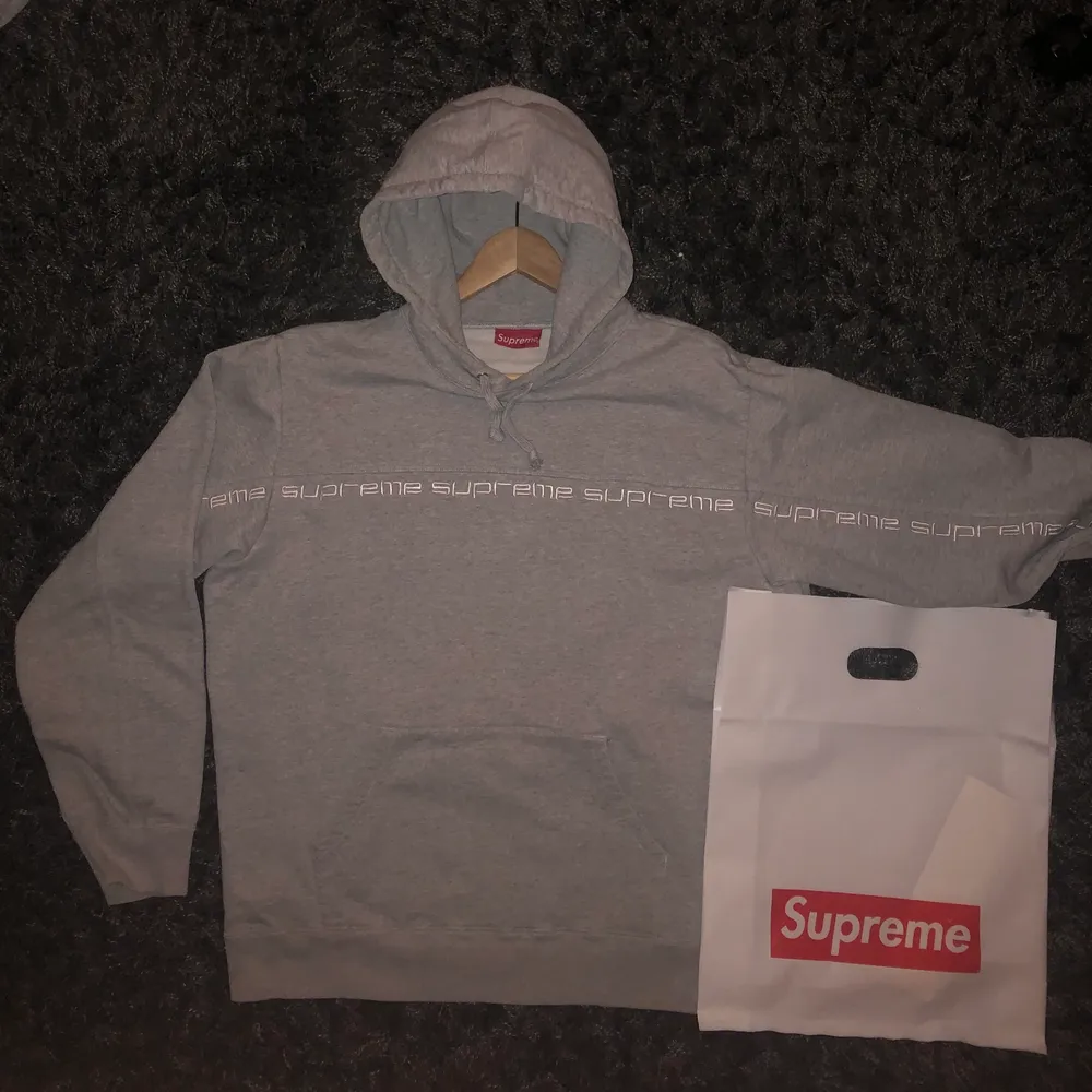 Säljer en Supreme Hoodie köpt från FW18 droppet. Plagget är i väldigt bra skick, endast använd några få gånger, samt endast tvättad ett fåtal gånger. Inga fläckar eller flaws. Hoodien är grå med vit broderad text som går från ärm till ärm. Backsidan av hoodien är helt grå (skriv för fler bilder). Både påse, klistermärke och kvitto är tillgängligt. Hoodien är i strlk Medium och  har en oversized look.. Hoodies.