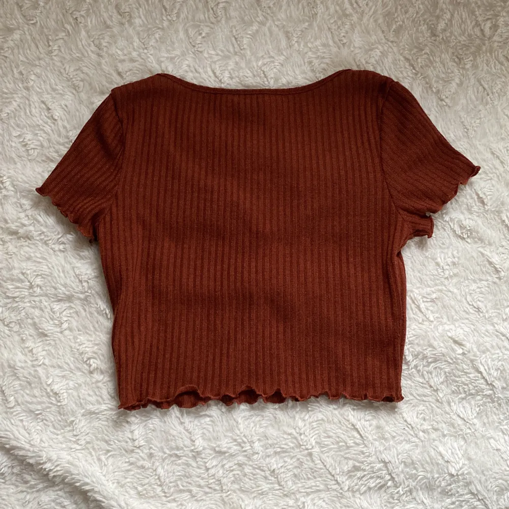 En brun, ribbad T-shirt från Shein. Vid nederdelen på tröjan och även vid ärmarnas slut är det som små volanger och vid halsen är det som en liten slits.. T-shirts.