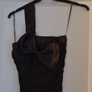 Klänning  - En brun klänning med rosett på. Materialet är stretchigt.  Spårbar frakt +66kr 