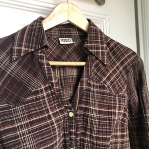 Skjorta - En snygg tajt skjorta med en vringning. Den har en åtsittande effekt längs midjan och är något croppad! Passar på någon med storlek XS/S!