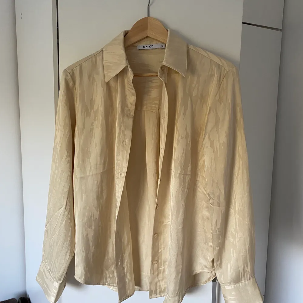En oversize silkig skjorta i en ljus beige färg, har ett svagt mönster på sig. Använd fåtal gånger så gott som ny. Storlek 32 men sitter som en 36/38. Skjortor.