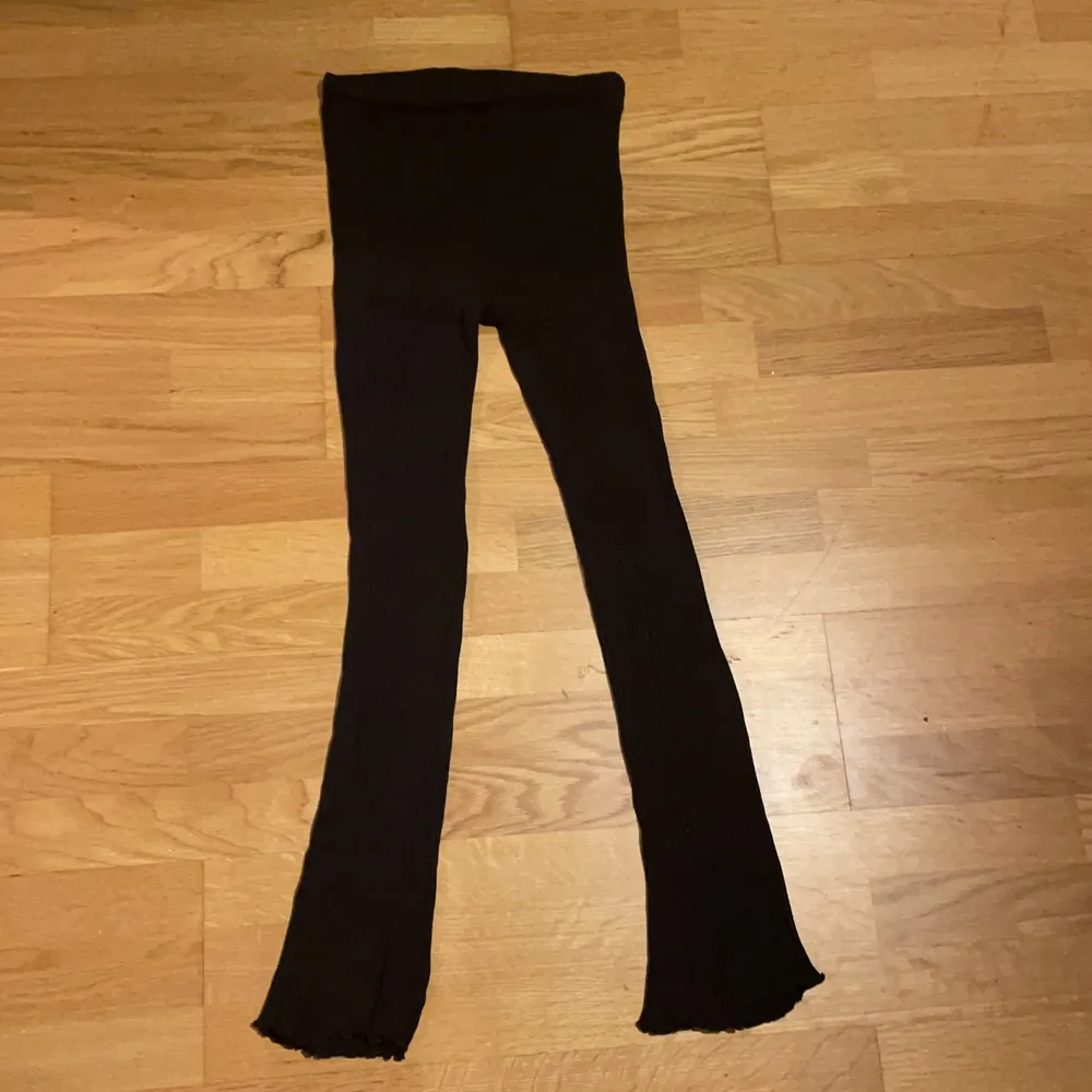 Svarta ribbade byxor med små volanger nedtill från Zara. Storlek s. Jeans & Byxor.