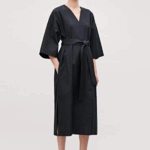 Svart/skiftande mörkblå kimono-inspirerad klänning från COS. Innerknäppning i tre lägen, och ytterknäppning, fungerar även fint öppen. Storlek XS men sitter oversized i modellen, sitter luftigt på mig som brukar bära S! Kan diskutera pris!