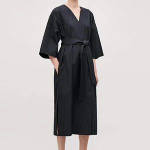 Omlott/Kimonoklänning COS - Svart/skiftande mörkblå kimono-inspirerad klänning från COS. Innerknäppning i tre lägen, och ytterknäppning, fungerar även fint öppen. Storlek XS men sitter oversized i modellen, sitter luftigt på mig som brukar bära S! Kan diskutera pris!
