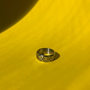 Bred ring  - Bred ring i rostfritt stål med glada och ledsna smileys på. Finns i storlek 10 (20 mm i innerdiameter) och säljs i mitt UF-företag :)