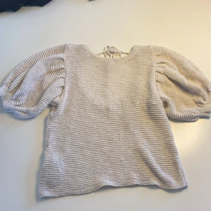 Blus - Stickad blus med öppen rygg och puffärmar. Trendig till sommaren