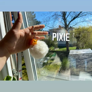 Nyckelring (Pixie) - Bege/vit med en guld gris berlick