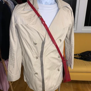 Mellanlång kappa - Säljer beige mellanlång kappa i färgen beige, skulle säga att storleken passar både M och S. Plagget är unisex och det ingår ett beige bälte som tillhör kappan. Obs! väskan ingår ej (stylingtips). Skriv för fler bilder.💕