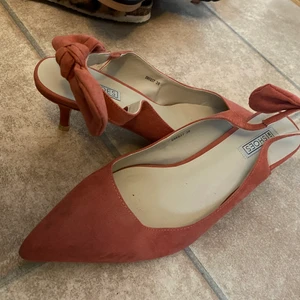 Klackskor - Oanvända klackskor ifrån Nelly med rosett på hälen. Storlek 38