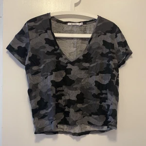 V-ringad T-shirt med militär mönster - En v-ringad T-shirt med grått militärmönster från nakd. Aldrig använd! Xs men passar s också!