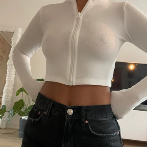 Tröja Niki studios - En långärmad zip up tröja i vitt ribbar material. Strl xs