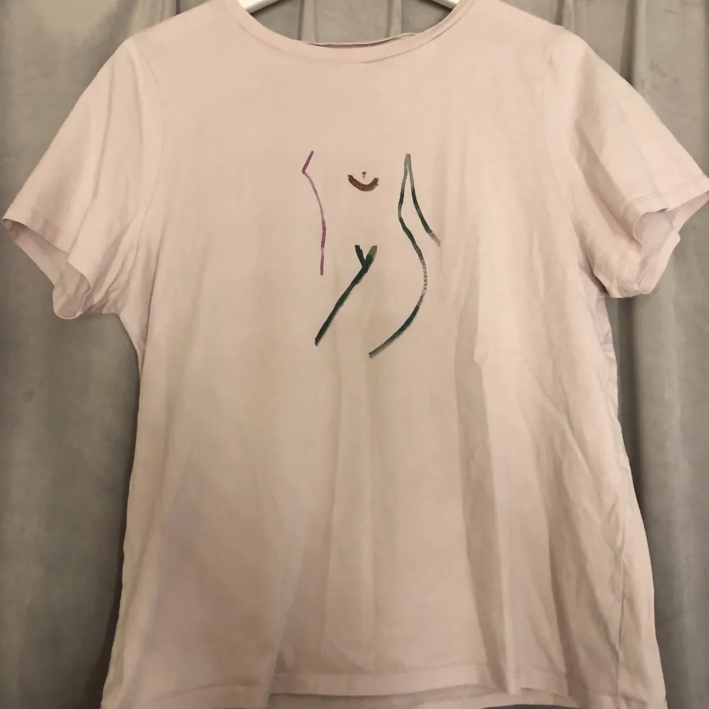Ljusrosa T-shirt med tryck av en kvinnokropp. Helfärgad på baksida. Storlek M men passar även S. Från NA-KD. Köpare står för frakt❤️‍🔥. T-shirts.