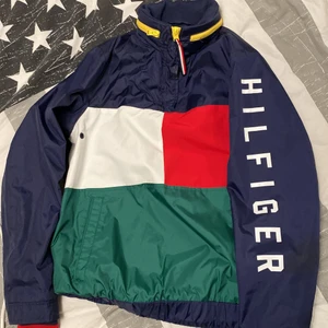 HILFIGER JACKA - säljer min helt oanvända vindjacka från tommy hilfiger. Den har en inbyggd luva i bak och fickor på sidan som man kan se på bilden! Går att ha en tjocktröja under utan några problemn Passar även XS!🌸 Köpaten står för frakt!☺️