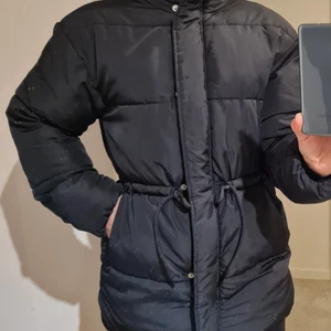 H&M Puffer - En medellång puffer från H&M. Storleken är xxs, men passar bra på mig som är xs-s. Vindslå, tryckknappar och band i midjan som går att knyta. Sparsamt använd, som ny. Kan skickas spårbart med posten för 66 kr.