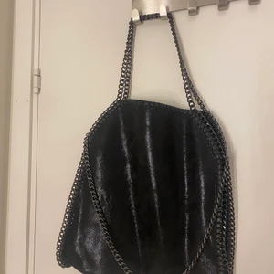 Axel väska svart med kedja  - Säljer en liknade stella mccartney väska/ tiamo.  Som jag aldrig har använt. Den har tre kedjor och är svart och lite skimrig/ glittrig. 🤩🎸