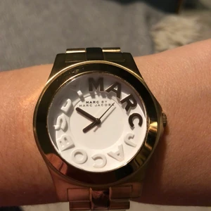 Klocka Marc by Marc Jacobs - Klocka i vit/gulguldtonat stål från Marc by Marc Jacobs modell Rivera, Ø40 mm. Batteribyte krävs. Är i väldigt bra skick, några rispor med inte så det är märkbart. Köpt på Marc by Marc Jacobs på NK i Stockholm. Har tyvärr inte kvar kvitto eller box.
