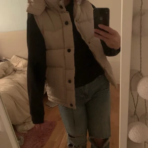 Dunväst  - Beige dunväst med avtagbar luva. Aldrig använd och lappen kvar fortfarande. Skulle säga att det är en S/M i storlek! Köparen står för frakten! ❌ då fler är intresserade så är det budgivning och budet ligger på 320kr + frakt! ❌