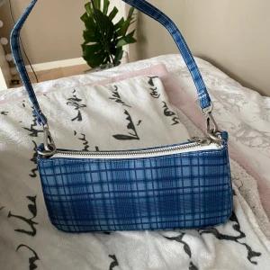 Blå väska - Rutig blå väska som är i jättebra skick!💙💙 vet inte frakten än men kan kolla upp om ni vill veta :)